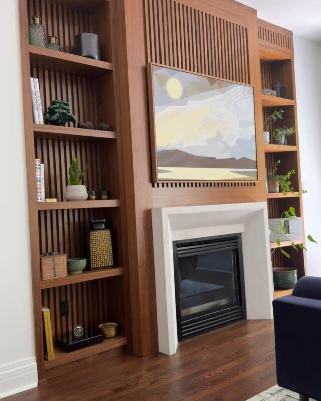 A modern dining and living room with a feature wall made of vertical wooden slats and built-in shelves. The walls add texture and visual interest to the space #customfireplace #customwall #customfurniture #customcabinets #customhomebuilderintoronto #customkitchens #moderndesign #customhome